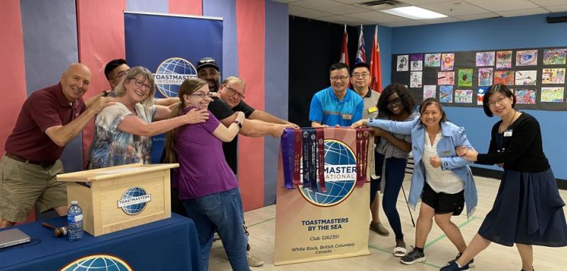 Fraser Heights Cornerstone Toastmasters club members raided Toastmasters by the Sea club’s banner in their hybrid meeting on August 20, 2023